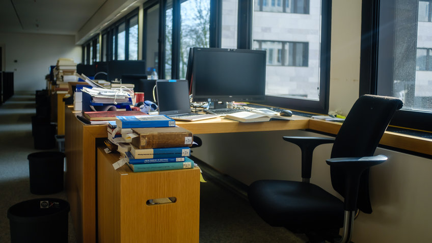 Desk with computers and many books in a library reading room