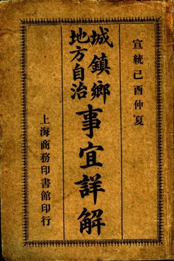 Ein altes chinesisches Buchcover mit vertikaler Kalligraphie in schwarzer Tinte auf braunem Papier. Der Haupttitel in der Mitte lautet „城鎮鄉地方自治事宜詳解“ (Ausführliche Erklärung der lokalen Selbstverwaltung in Städten, Gemeinden und Dörfern). Am rechten Rand steht „宣統己酉仲夏“ (Mittsommer im Jahr Jiyou der Xuantong-Ära, 1909), links „上海商務印書館印行“ (Veröffentlicht vom Shanghaier Handelsverlag). Ein dekorativer Rahmen umgibt den Text.