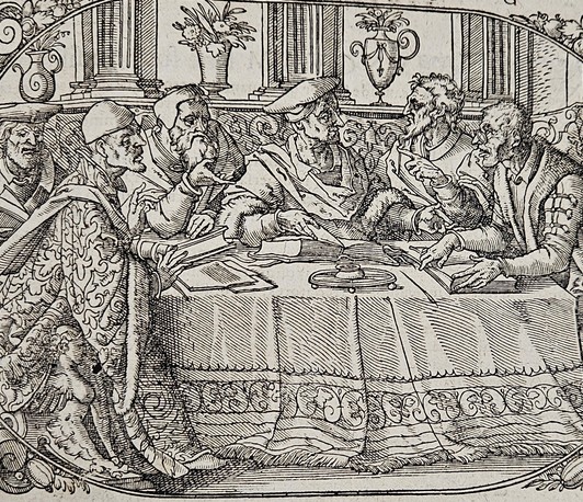 Historical woodcut-style illustration showing a group of seven men in Renaissance clothing engaged in discussion around a richly decorated table, surrounded by ornamental floral borders.